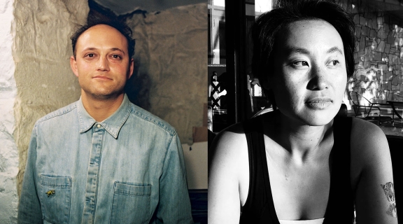 two poets, one in blue denim buttoned up shirt in a basement; one in low-neck sleeveless top, tattoo on left arm