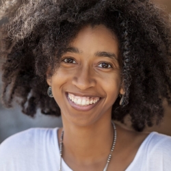 poet in dark curly locks, brown skin and eyes, white open neck shirt, broad smile