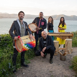 a band of musicians with their instruments at the shore of a grand mountain lake in the global south