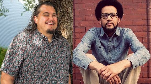 two poets, one in checked shirt, long dark hair + thin beard, smiling near a tree; one seated, hands clasped, blue shirt + tan pants, curly dark hair, each wearing eyeglasses