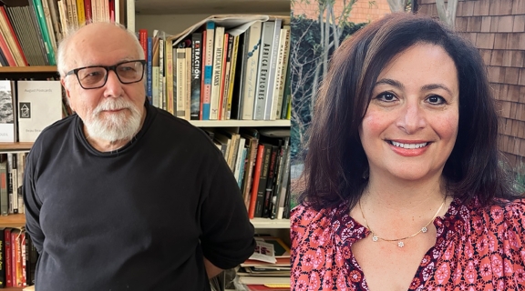 a man in white beard and dark shirt before shelves of books; a woman in straight brown hair and red shirt, both poets are smiling