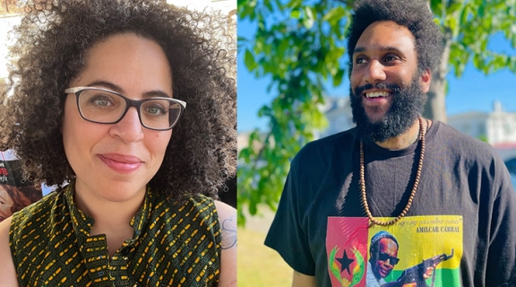 curly dark-haired woman in glasses with a green patterned shirt smiling + a smiling man, dark hair and beard wearing a beaded necklace over black t-shirt with colorful image indentified as Amilcar Cabral, a tree at their back
