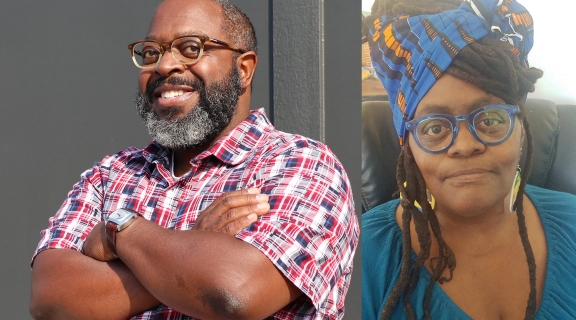 two poets, one with grey-black beard, short cropped hair, pink patterned shirt, arms crossed, smiling; one in long brown dreads + blue-gold patterned headwrap, blue v-neck top; both with deep brown complexion and wearing colorful eyeglasses