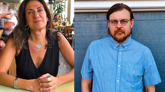 a poet with long brown hair clasps her hands, smiling in a cafe setting; a poet in brown hair beard & glasses, in a blue buttoned shit before a blue wall